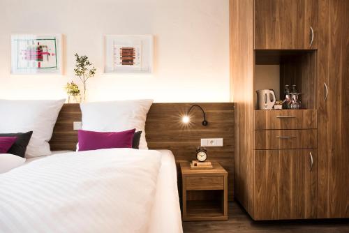 明斯特Alexianer Hotel am Wasserturm的一间卧室配有一张带白色床单和紫色枕头的床