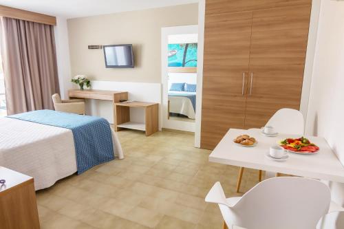 帕格拉新海洋公寓式酒店的酒店客房,配有一张床和一张桌子,上面有盘子的食物