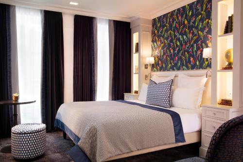 巴黎蒙赫酒店的卧室配有一张床,墙上挂有绘画作品