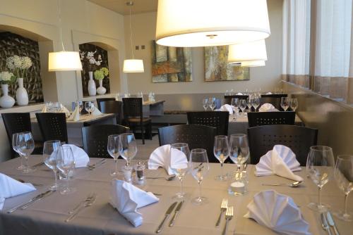 Uzwil巴恩霍夫酒店的用餐室配有带玻璃杯和餐巾的桌子