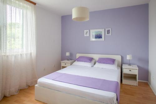 科尔丘拉Apartments Chiara的白色卧室配有一张带紫色枕头的大床