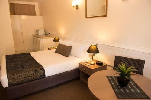 布里斯班花园城汽车旅馆的酒店客房,设有一张床和两张桌子