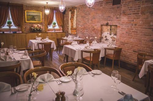 塔尔图玛格丽塔精品酒店的一间设有白色桌椅的餐厅,拥有砖墙