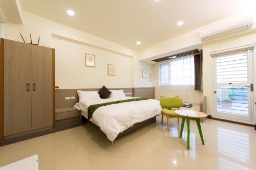 台东桀立民宿的一间卧室配有一张大床和一张绿色椅子