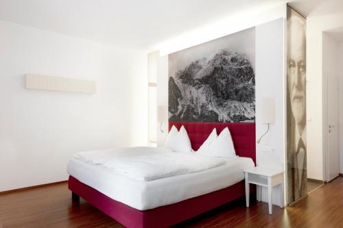 派尔巴赫Hotel Payerbacherhof的卧室配有白色床和红色床头板