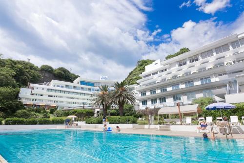 西伊豆町堂岛温泉日式旅馆的酒店游泳池的背景是一座大型建筑