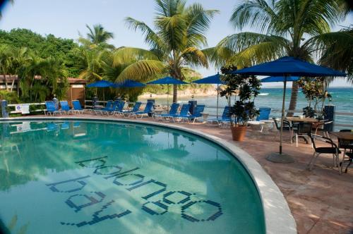 BolongoBolongo Bay Beach Resort All Inclusive的海滩上带椅子和遮阳伞的游泳池