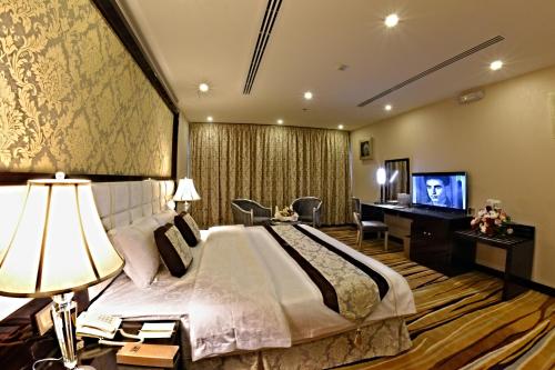 胡富夫花园广场酒店的一间卧室配有一张床、一张书桌和一台电视