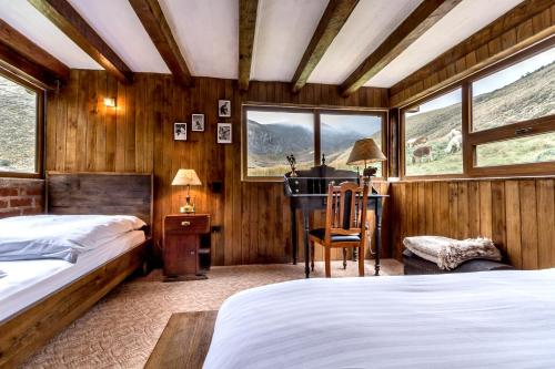 Chimborazo钦博拉索山林小屋的一间卧室设有两张床、一张桌子和窗户。