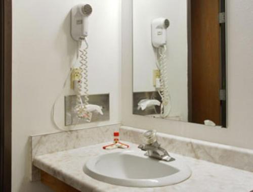 Becker贝克尔酒店及套房的一间带水槽和镜子的浴室以及一部电话