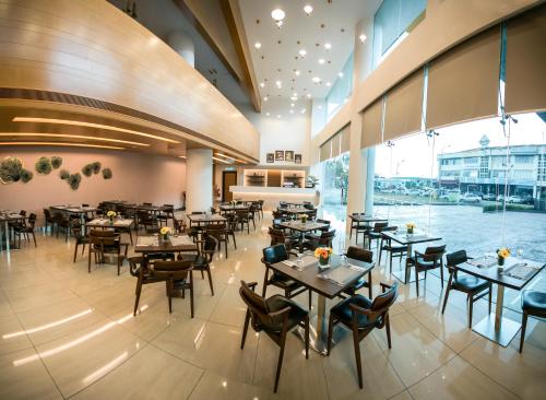 新山新山V8酒店的餐厅设有桌椅和大窗户。