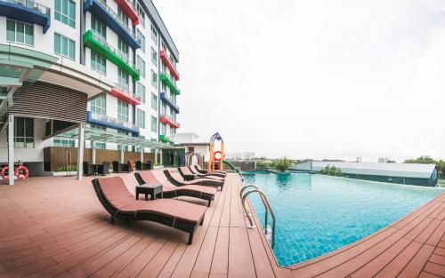 新山新山V8酒店的一座带长椅的游泳池,位于大楼旁