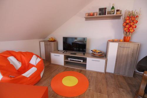 Kájov橙色阁楼公寓的客厅配有橙色椅子和电视
