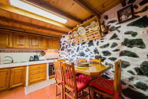 Calheta de Nesquim阿德加韦利亚度假屋的厨房配有桌椅和石墙
