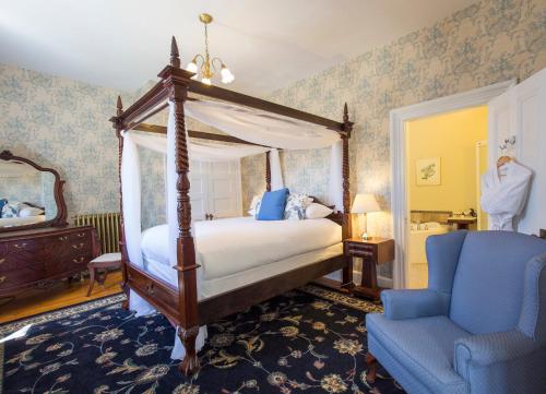 安纳波利斯罗亚尔奎恩安妮酒店的一间卧室配有天蓬床和蓝椅