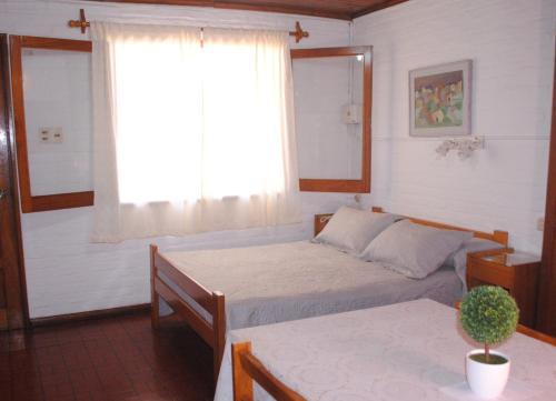 特玛斯德戴曼Bungalows Archi的一间卧室设有两张床、一个窗口和一张桌子