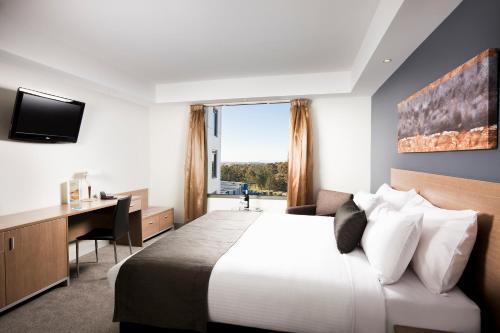 墨尔本Mantra Melbourne Airport的配有一张床、一张书桌和一扇窗户的酒店客房