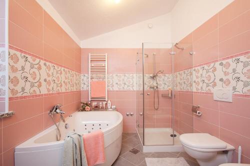 拉宾Apartments Bellistra Labin的粉红色的浴室设有浴缸和卫生间