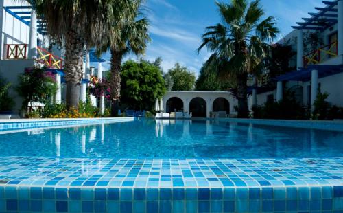 博德鲁姆Su Hotel - Bodrum的一座棕榈树游泳池和一座建筑