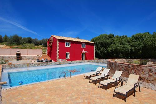 埃斯坦巴金塔多斯瓦莱斯葡萄酒庄园旅馆的一个带椅子的游泳池以及一座红色的房子