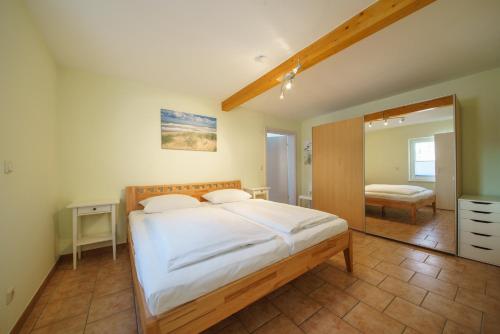 塞巴特阿尔贝克Ferienwohnungen Wollenberg的卧室配有一张白色大床和镜子