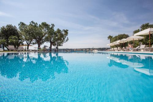 萨罗Hotel Spiaggia d'Oro - Charme & Boutique - Garda Lake Collection的一座带蓝色水和遮阳伞的大型游泳池