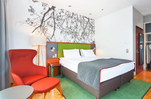 赫尔辛基赫尔辛基市中心假日酒店的一间卧室配有一张床和一张红色椅子