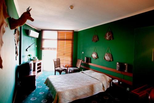 利马索尔西尔瓦酒店的一间卧室设有绿色的墙壁,卧室的墙上设有一张带鹿头的床。