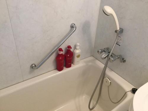 丰见城市大花园冲绳酒店的浴室设有浴缸,配有2瓶红色的瓶子