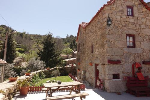 塞亚Casas da Fonte - Serra da Estrela的石头建筑,前面设有桌子和长凳