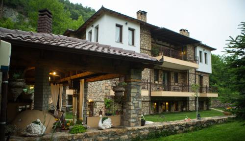 卡托劳塔翁Archontiko Emmanouilidi Suites的一座大型石头房子,在庭院内设有一个阳台