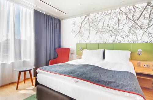 赫尔辛基赫尔辛基市中心假日酒店的一间卧室配有一张大床和一张红色椅子
