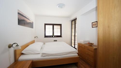 鲁容贝罗克Vila Olympia - Apartmán Olympia 3的一间卧室配有一张床、一个梳妆台和一扇窗户。