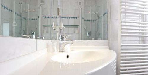 巴德索登陶努斯巴特索登森林酒店的白色的浴室设有水槽和镜子