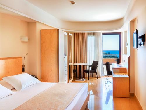 陶尔米纳Taormina Panoramic Hotel的酒店客房设有一张床铺和一张桌子,享有美景。