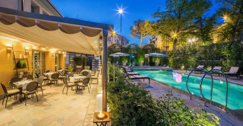 佛罗伦萨维莱苏拉诺酒店的酒店庭院设有游泳池和桌椅