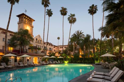 里弗赛德米申Spa酒店的黄昏时分,酒店游泳池设有椅子和棕榈树