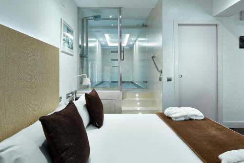 巴塞罗那巴塞罗那加乌丁特套房酒店的一间卧室设有一张大床和淋浴