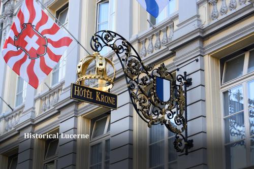 卢塞恩卢塞恩王冠老城酒店的建筑一侧的标志,带有旗帜