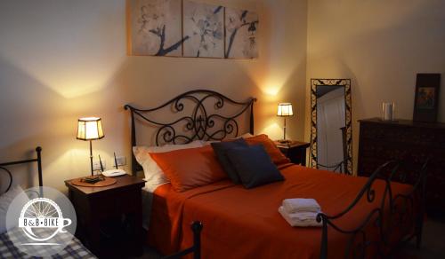 巴尼奥雷焦Bed and Breakfast Bike的一间卧室配有橙色床、两盏灯和一面镜子