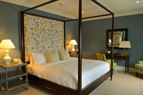 Quogue夸格俱乐部酒店的一间卧室配有一张天蓬床和一张书桌