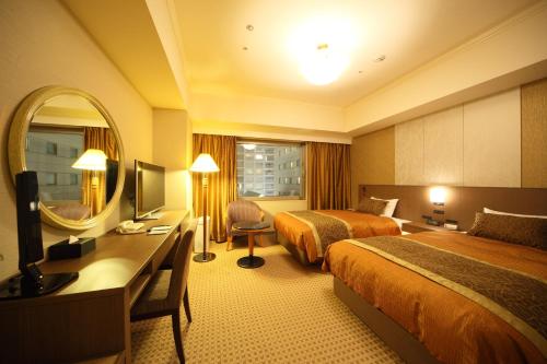 长野长野都会酒店的酒店客房设有两张床、一张桌子和一面镜子