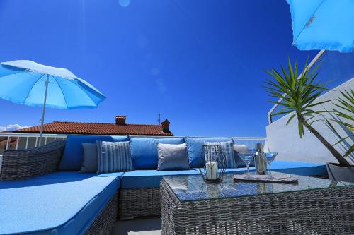斯普利特Holiday Apartments Split的蓝色的沙发、桌子和雨伞