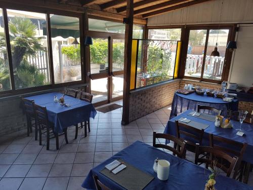 安齐奥玛丽娜奥柏格别墅酒店的餐厅设有蓝色的桌椅和窗户。