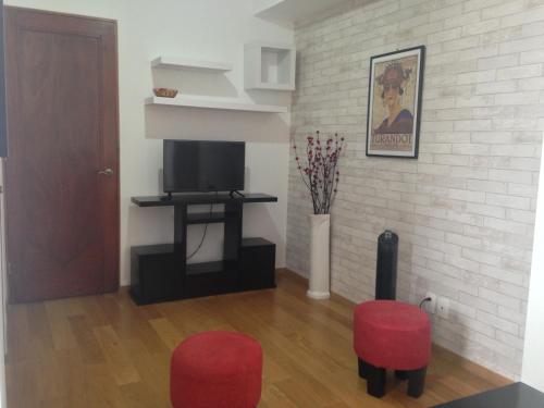 墨西哥城市区美丽公寓的客厅配有2把红色椅子和电视