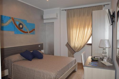 特罗佩阿La Conchiglia的一间卧室配有一张带蓝色枕头的床和一张书桌
