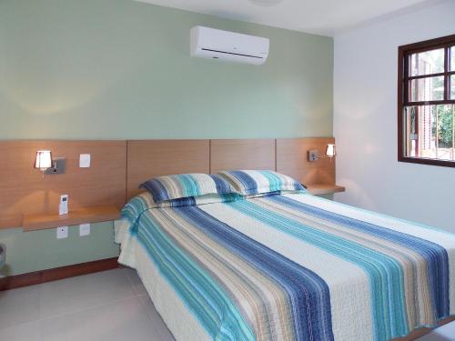 阿布拉奥Ancoradouro Flats的一间卧室配有带条纹毯子的床