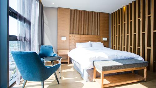 晋州市J广场婚庆酒店的一间卧室配有一张床和两张蓝色椅子