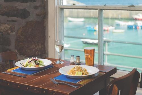 毛斯尔航船酒店的一张桌子,上面放着两盘食物和一杯葡萄酒