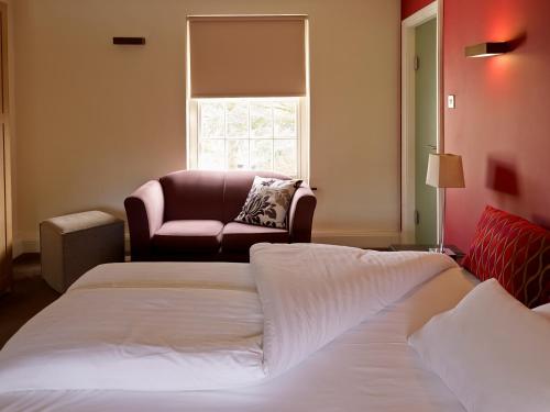 莱斯特奇妮酒店的一间卧室设有两张床、一把椅子和一个窗户。